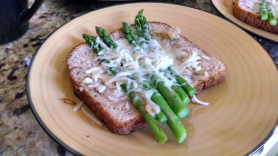 A slice of 12 grain toast with melted gruyere and asparagus
